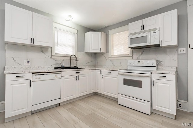 kitchen with white appliances, a healthy amount of sunlight, sink, and white cabinetry