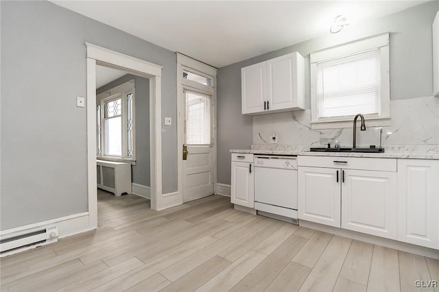 kitchen featuring white dishwasher, sink, light stone countertops, white cabinetry, and light hardwood / wood-style flooring