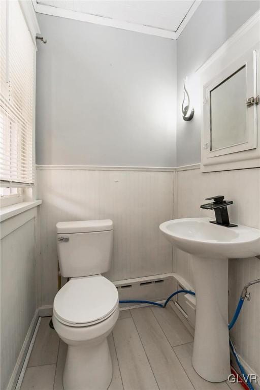 bathroom featuring hardwood / wood-style flooring, toilet, and crown molding