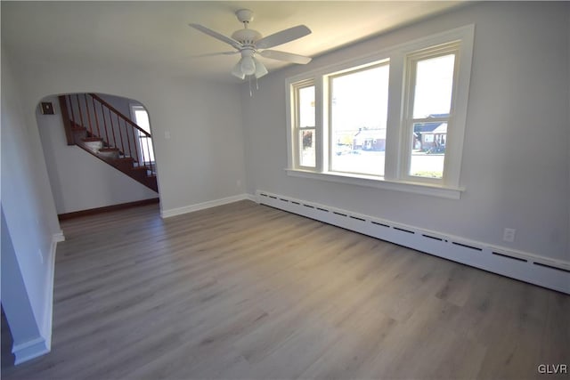 spare room featuring ceiling fan, wood-type flooring, and a baseboard heating unit