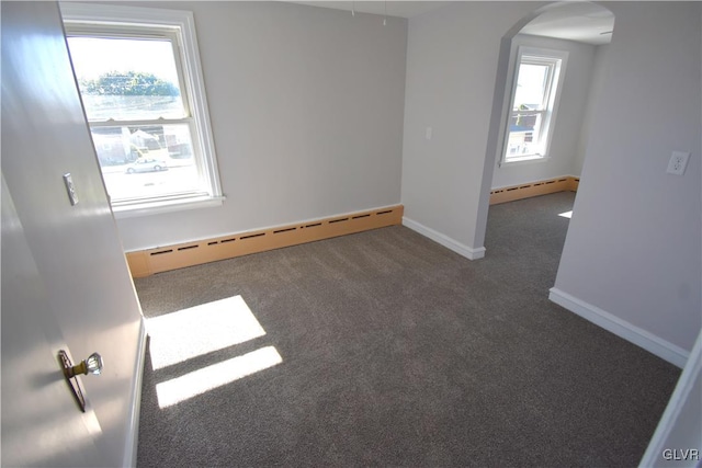 carpeted empty room featuring a wealth of natural light and baseboard heating