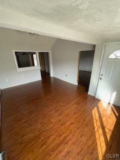 unfurnished living room featuring a textured ceiling and dark hardwood / wood-style floors