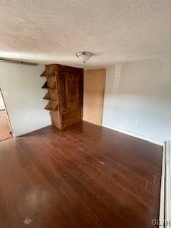 interior space with a textured ceiling and dark wood-type flooring