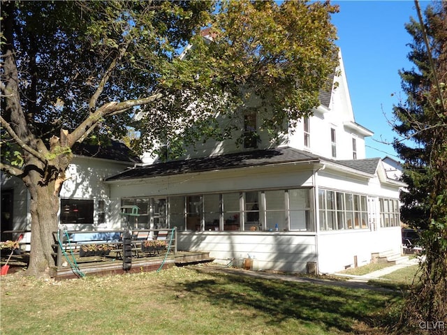 rear view of house featuring a yard and a sunroom