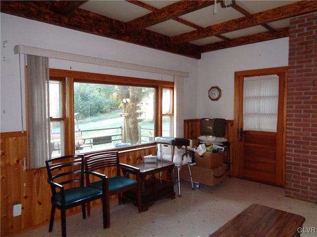 sitting room featuring a wealth of natural light, beamed ceiling, wooden walls, and coffered ceiling