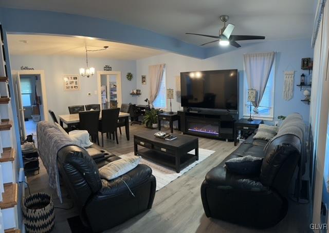 living room with light hardwood / wood-style flooring and ceiling fan with notable chandelier