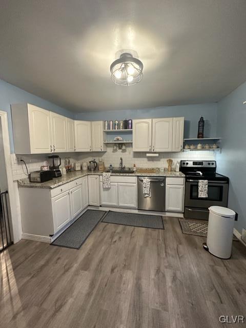 kitchen with decorative backsplash, white cabinets, stainless steel appliances, and hardwood / wood-style floors