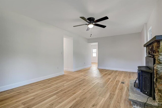 3331 Walnut St, Bethlehem Twp, PA 18020 - unfurnished living room featuring a wood stove, ceiling fan, light wood-type flooring, and baseboards