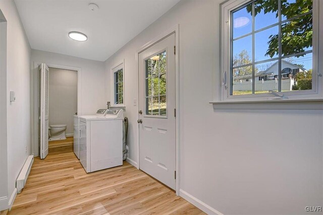 washroom featuring a healthy amount of sunlight, washer and dryer, a baseboard radiator, and light hardwood / wood-style floors