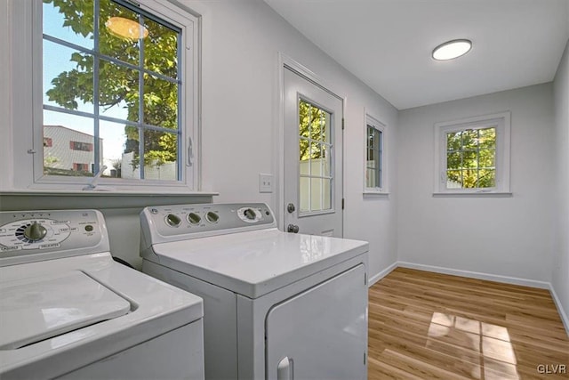 clothes washing area with a wealth of natural light, light wood-type flooring, and independent washer and dryer