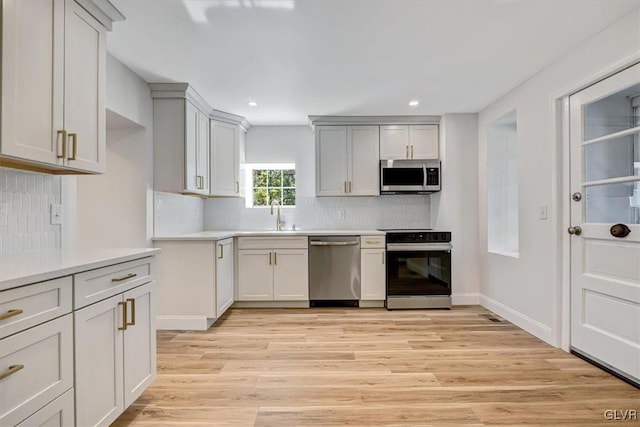 kitchen with light hardwood / wood-style flooring, sink, appliances with stainless steel finishes, and tasteful backsplash