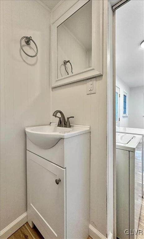 bathroom with wood-type flooring, vanity, and washer / dryer