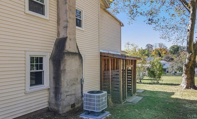 view of side of home featuring a yard and central AC