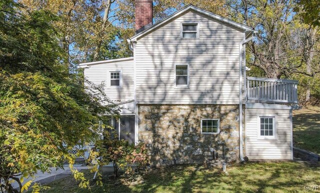 3331 Walnut St, Bethlehem Twp, PA 18020 - rear view of house featuring a chimney, stone siding, a balcony, and a lawn