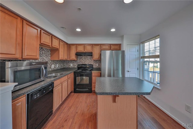 kitchen featuring a sink, black appliances, under cabinet range hood, dark countertops, and tasteful backsplash