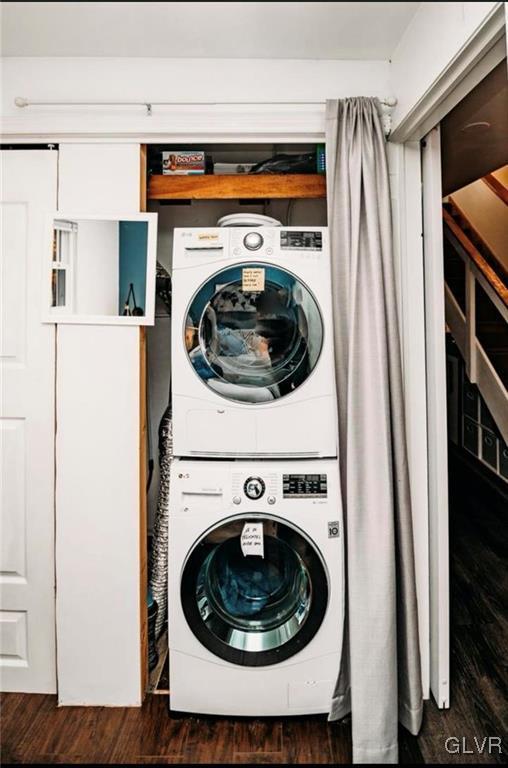 clothes washing area with dark wood-type flooring and stacked washing maching and dryer