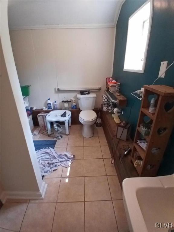 bathroom with ornamental molding, toilet, and tile patterned flooring