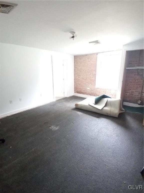 empty room featuring visible vents and brick wall