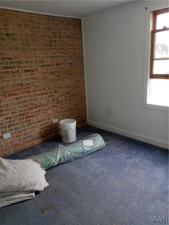 unfurnished bedroom with multiple windows, carpet, baseboards, and brick wall