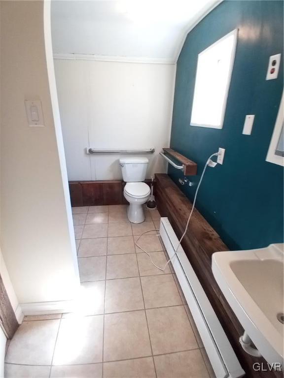 bathroom with a sink, vaulted ceiling, a baseboard heating unit, tile patterned floors, and toilet