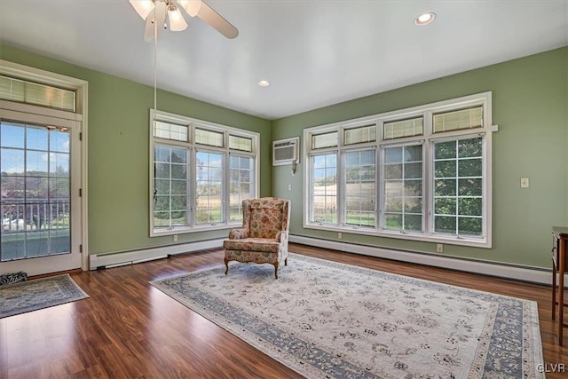 living area with a healthy amount of sunlight, baseboard heating, and dark wood-type flooring