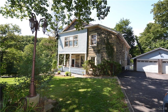 view of front facade featuring a garage, covered porch, an outdoor structure, and a front lawn