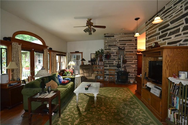 living room featuring a wood stove, wood finished floors, and a ceiling fan