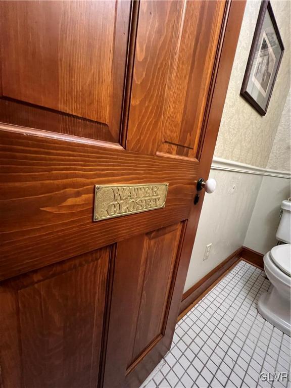 bathroom featuring tile patterned flooring, toilet, and baseboards