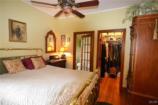 bedroom with ensuite bath, wood finished floors, a closet, crown molding, and a spacious closet