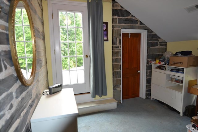 doorway to outside with carpet flooring and vaulted ceiling