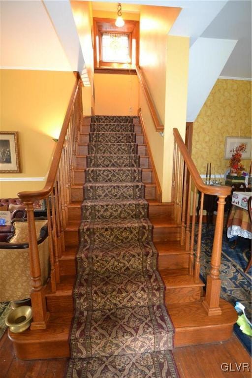 stairway featuring wallpapered walls and wood finished floors