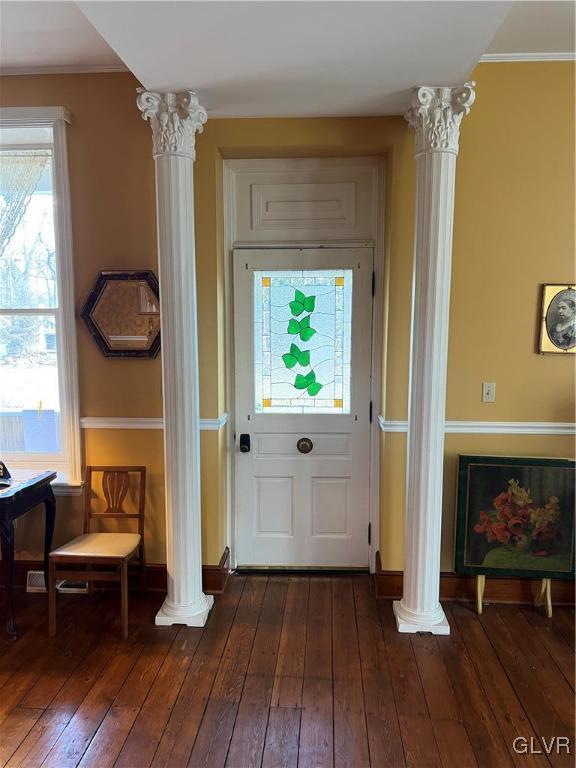 doorway with dark wood finished floors, decorative columns, and baseboards