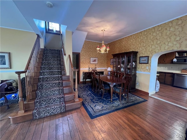 dining room with hardwood / wood-style flooring, stairway, arched walkways, wallpapered walls, and a chandelier