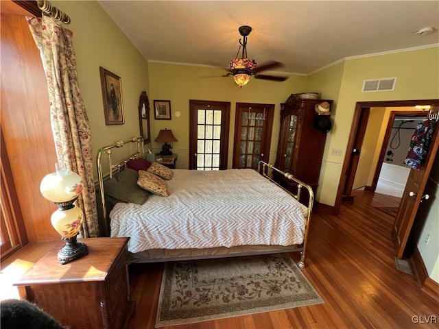 bedroom with baseboards, wood finished floors, visible vents, and ornamental molding