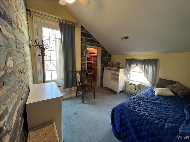 carpeted bedroom with a walk in closet, vaulted ceiling, visible vents, and ceiling fan