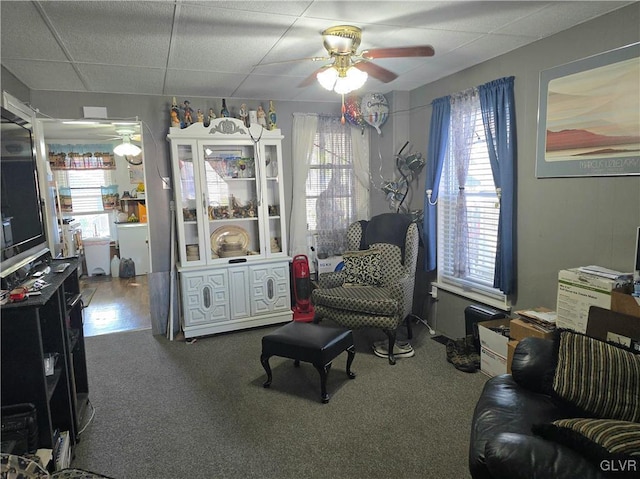 sitting room with a drop ceiling, ceiling fan, and carpet