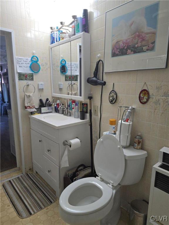 bathroom featuring vanity, tile walls, and toilet