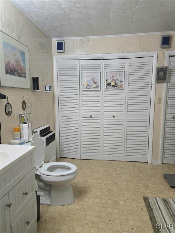 bathroom with crown molding, vanity, toilet, and tile walls