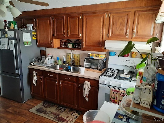 kitchen featuring white gas range, sink, stainless steel fridge, dark hardwood / wood-style flooring, and ceiling fan