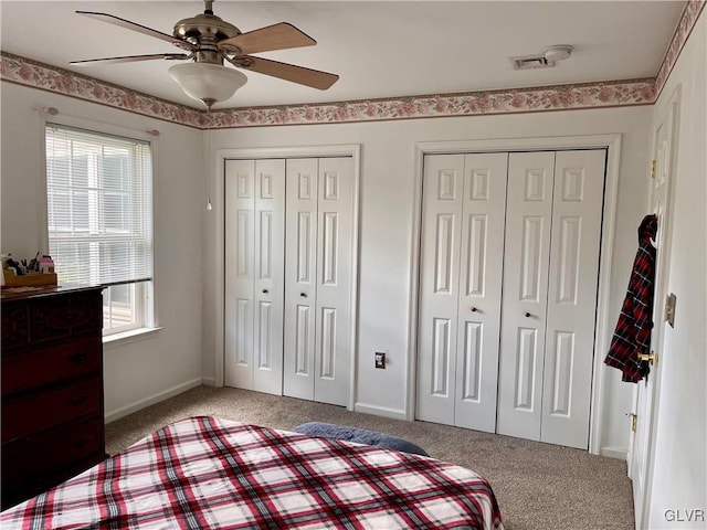 bedroom featuring multiple windows, two closets, and ceiling fan