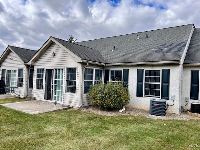 rear view of house featuring cooling unit, a patio area, and a lawn