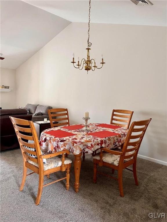 dining room featuring a chandelier, vaulted ceiling, and carpet flooring