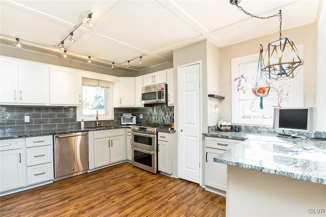 kitchen featuring tasteful backsplash, stainless steel appliances, pendant lighting, dark hardwood / wood-style floors, and white cabinetry