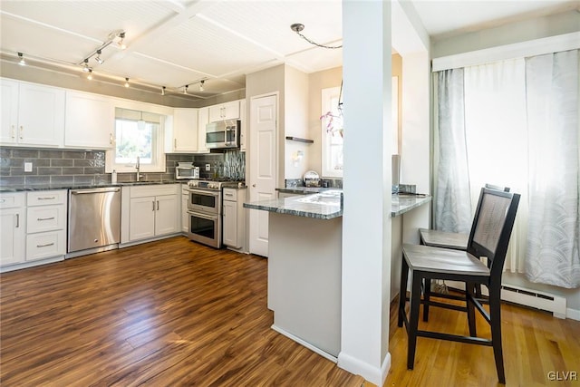 kitchen featuring kitchen peninsula, white cabinetry, dark hardwood / wood-style flooring, and appliances with stainless steel finishes