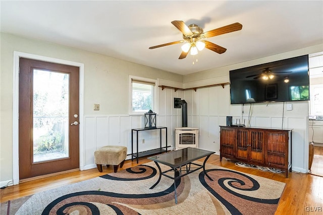 living room featuring a wood stove, light hardwood / wood-style flooring, and ceiling fan