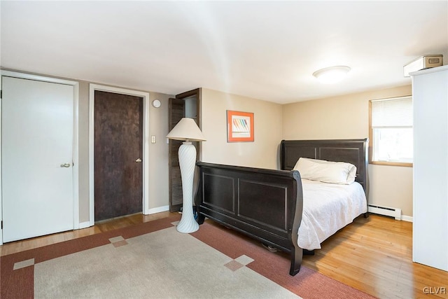 unfurnished bedroom featuring hardwood / wood-style floors and a baseboard heating unit