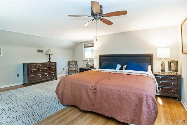 bedroom with ceiling fan, light hardwood / wood-style flooring, and vaulted ceiling