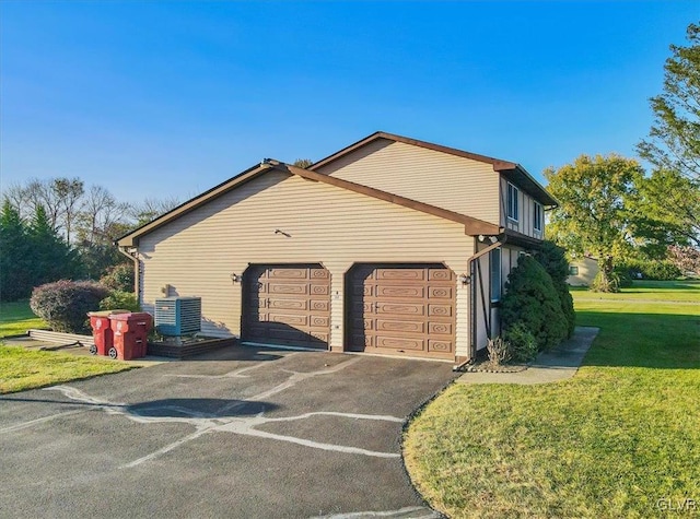 view of home's exterior with a yard, central air condition unit, and a garage