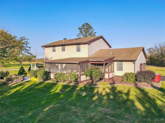 rear view of house with a yard and a sunroom