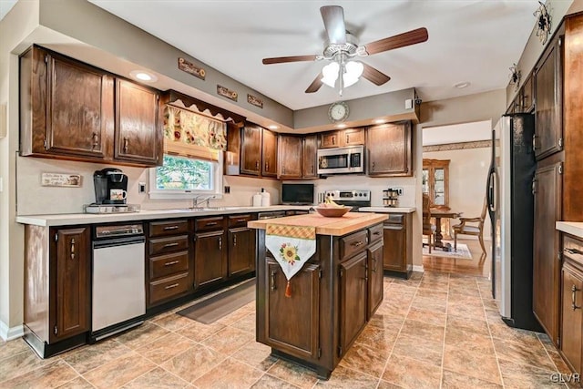 kitchen with wooden counters, a kitchen island, stainless steel appliances, sink, and dark brown cabinetry